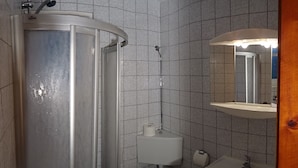 Une salle de bain équipée d’une douche, de toilettes, d’un lavabo et d’un miroir.