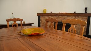Une table de salle à manger en bois, avec des chaises, un vase et une bougie posés sur la cheminée.
