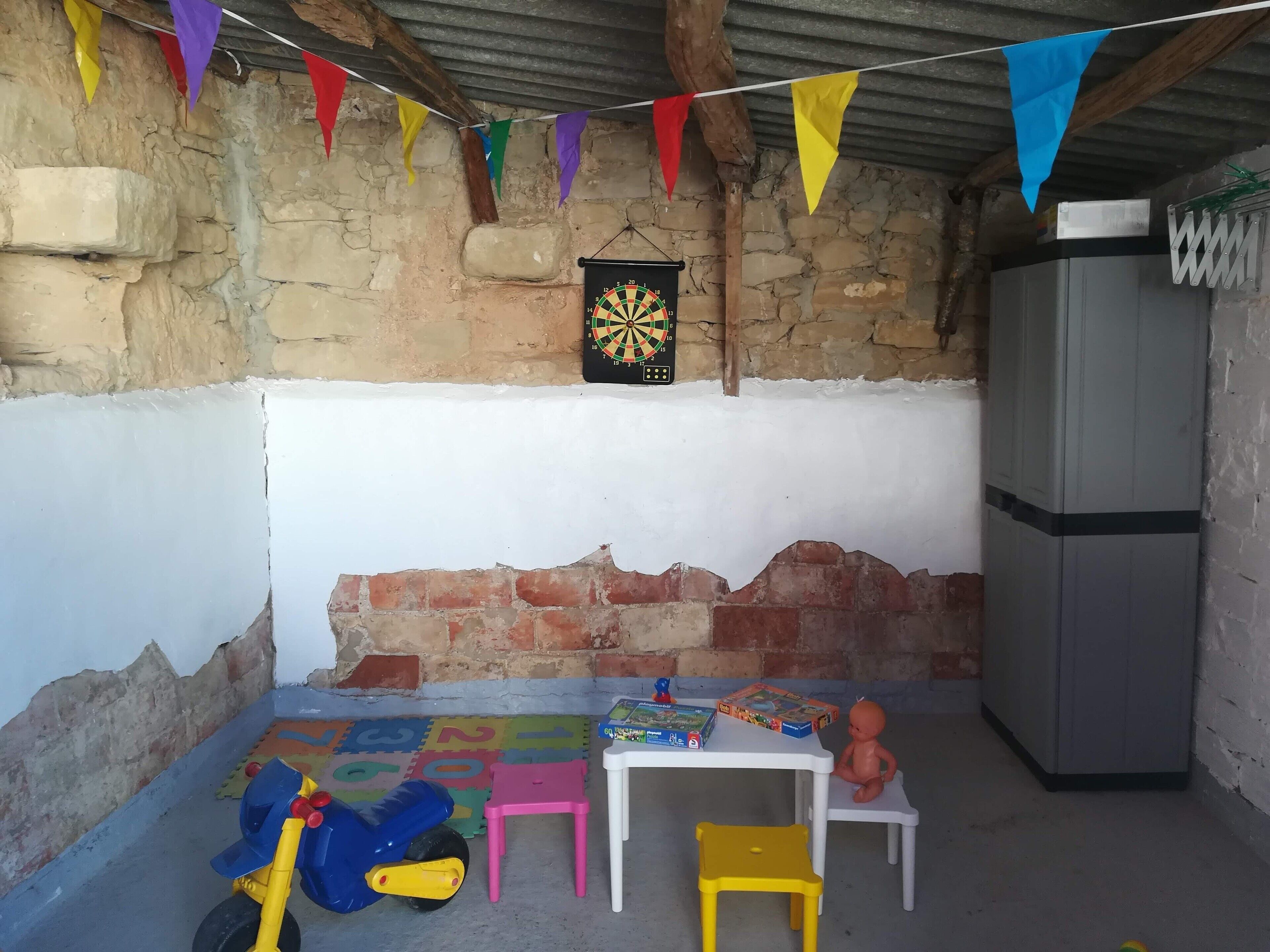 Una stanza rustica con un bersaglio da freccette, giochi per bambini e un frigorifero.