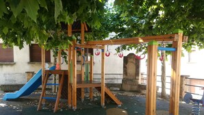 Une aire de jeux avec un toboggan, des structures d’escalade et une balançoire.