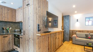 A modern kitchen with wooden cabinetry, a built-in oven, and a flat-screen TV mounted on the wall. - Elegant apartment - 6 guests near slopes (Val-d'Isère)