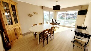 Un coin repas comprenant une table ronde, des chaises en bois, un buffet et un téléviseur.