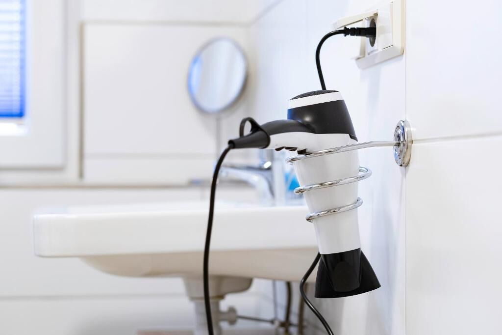 A bathroom with a white sink and a hairdryer mounted on the wall.