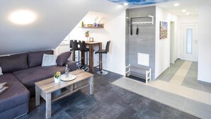 Uma sala de estar moderna com sofá, mesa de centro e área de jantar com cadeiras e uma pequena mesa.