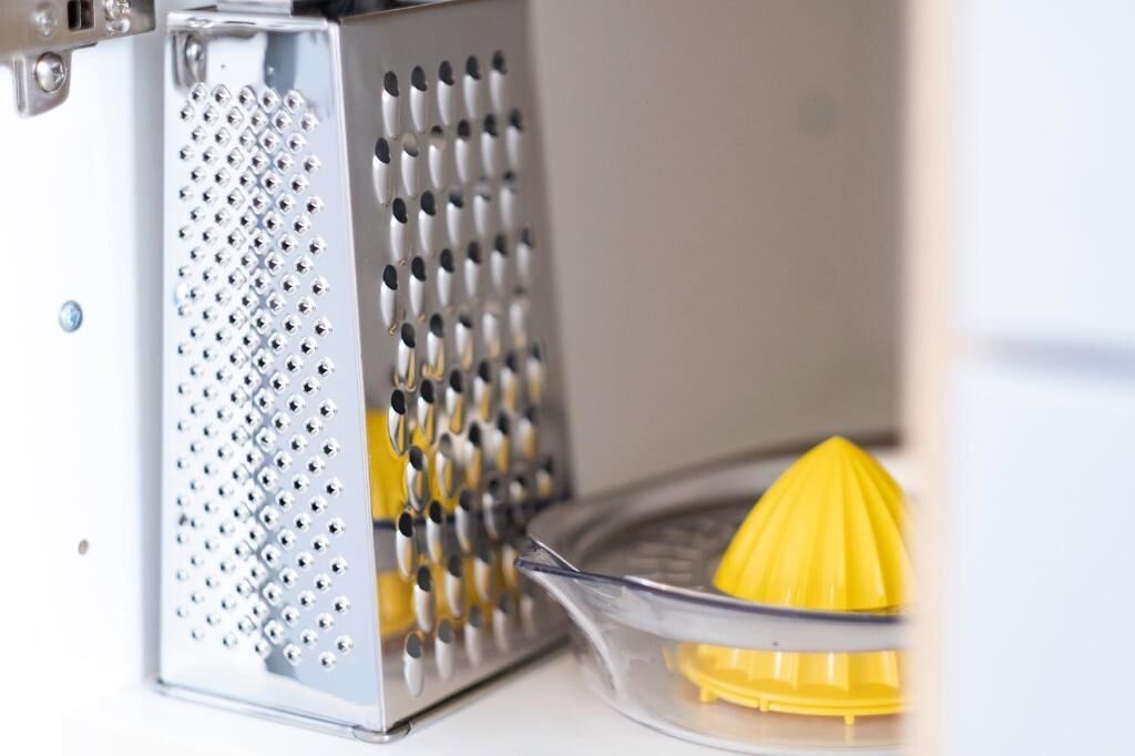 A kitchen with a grater and a yellow citrus juicer.