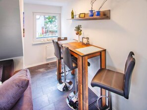 A dining area with a wooden table, four chairs, and a window with a view of the outside.