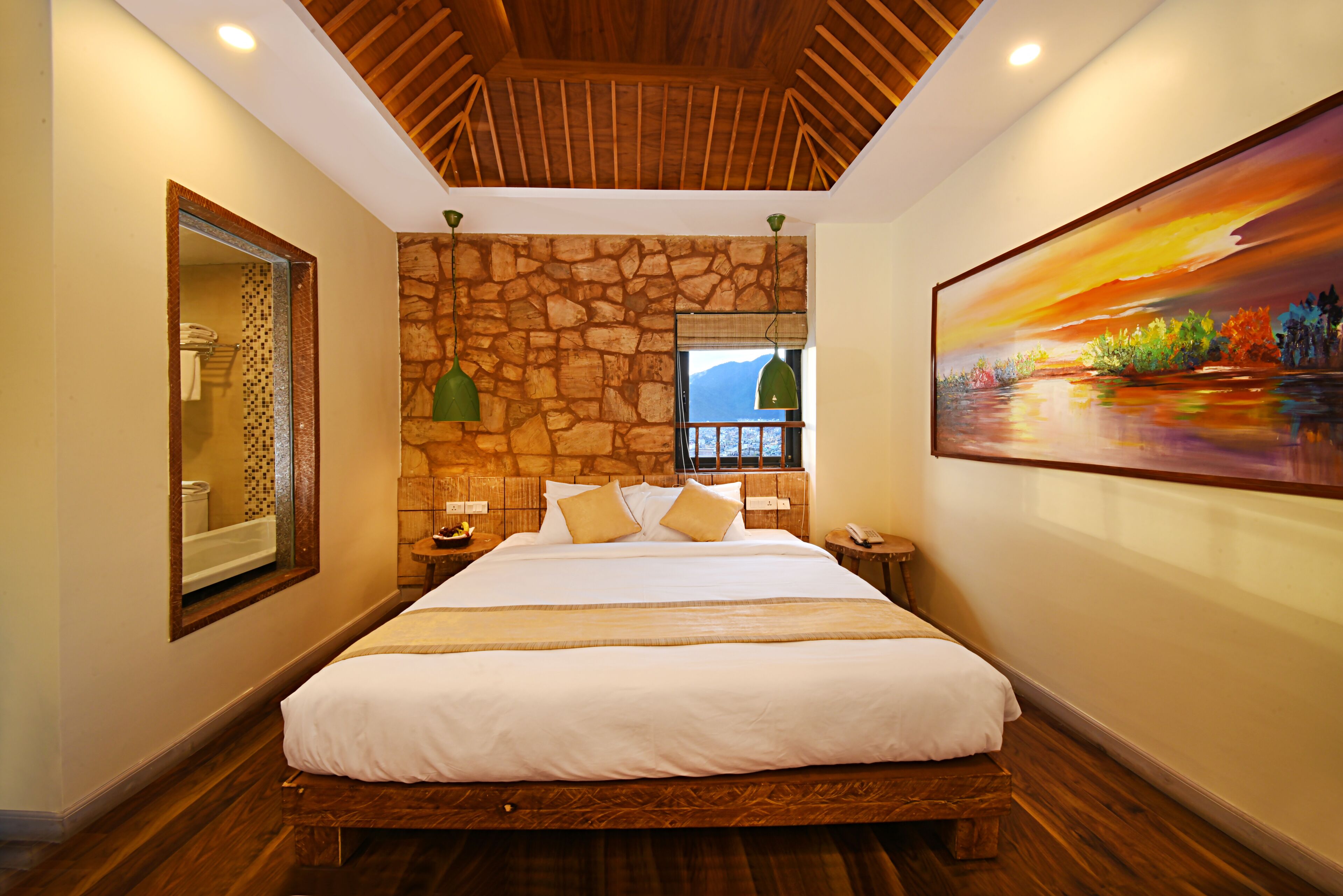 A spacious bedroom with a large bed, stone wall, wooden ceiling, and a painting on the wall.
