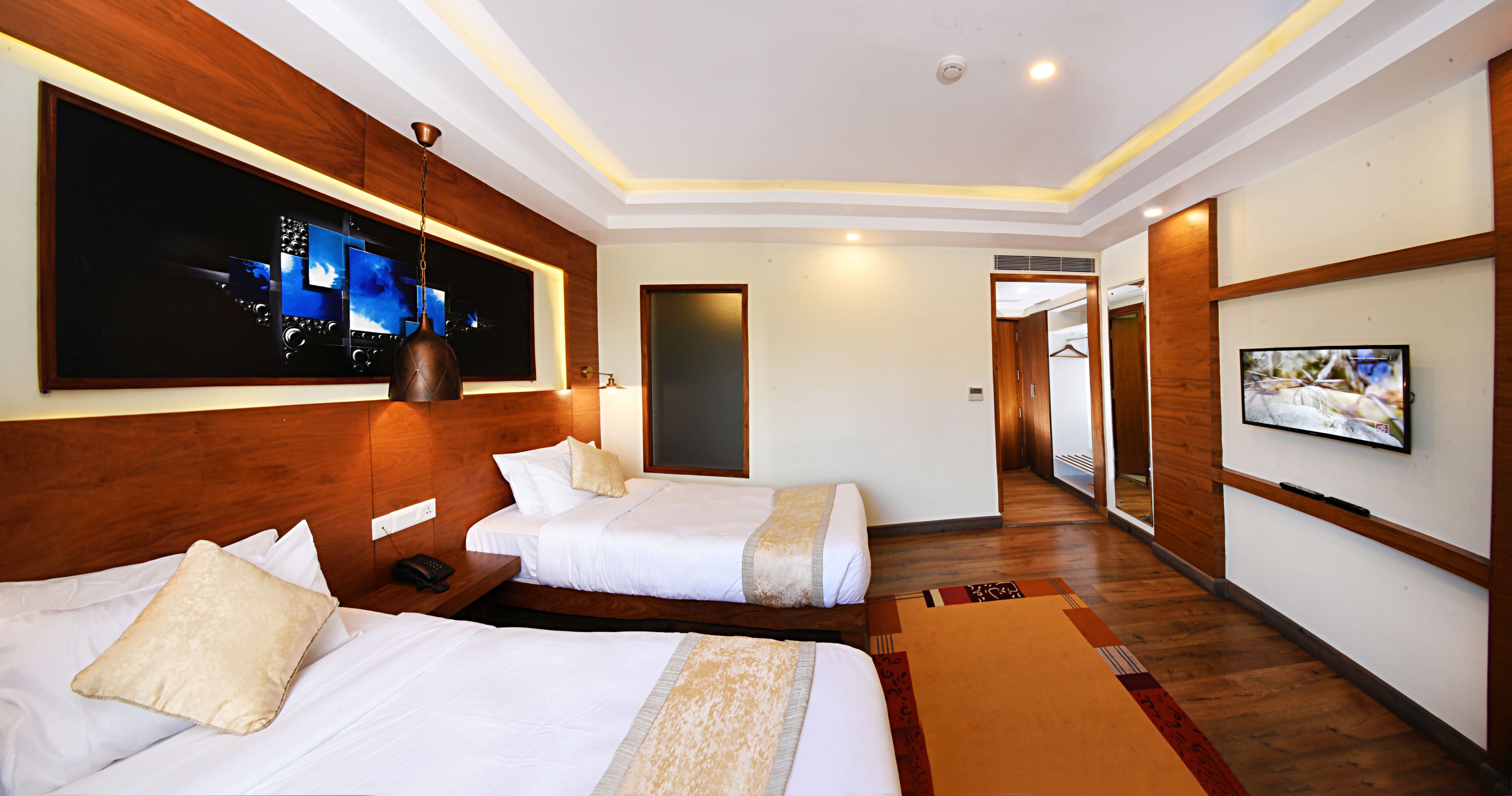 A hotel room with two beds, a TV, a large window, and a wooden headboard.