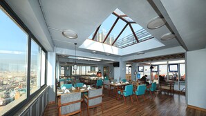 Un restaurante espacioso con techos altos, ventanas grandes y tragaluces. Mesas y sillas dispuestas para comer.