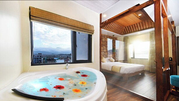 Un baño con una bañera grande, una ventana que ofrece vistas a un paisaje urbano y un techo de madera.