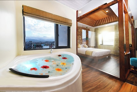 A bathroom with a large bathtub, a window with a view of a cityscape, and a wooden ceiling.