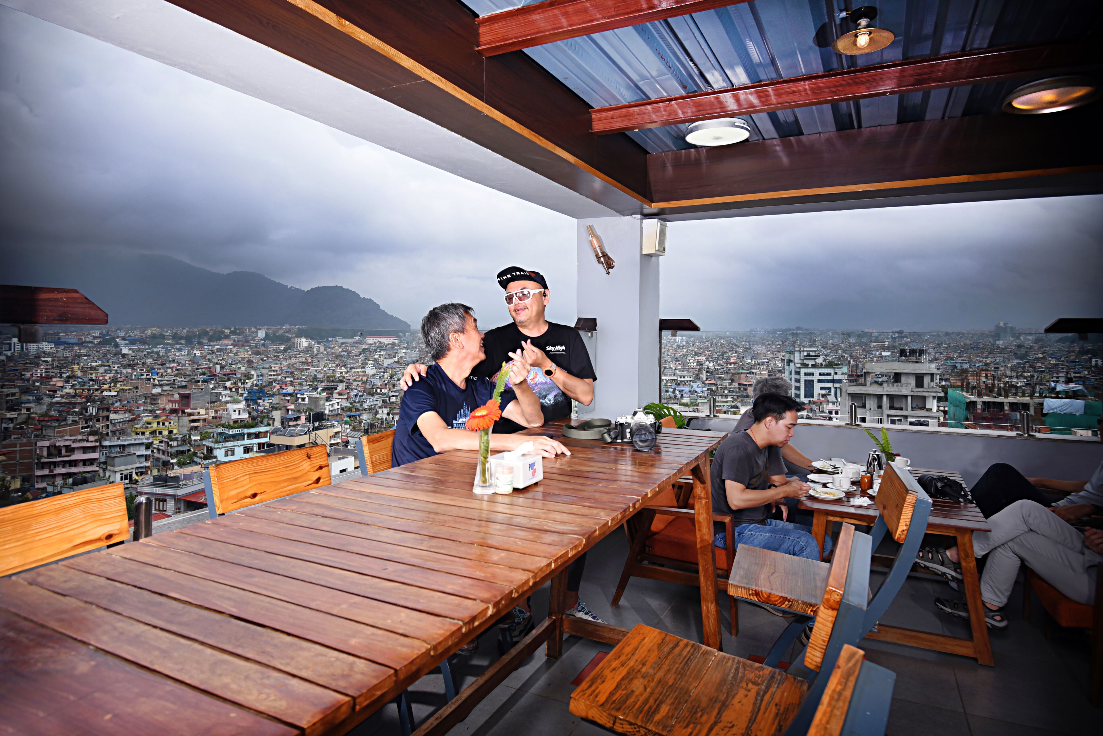 A dining area with a wooden table and chairs, a city view, and a modern ceiling design.