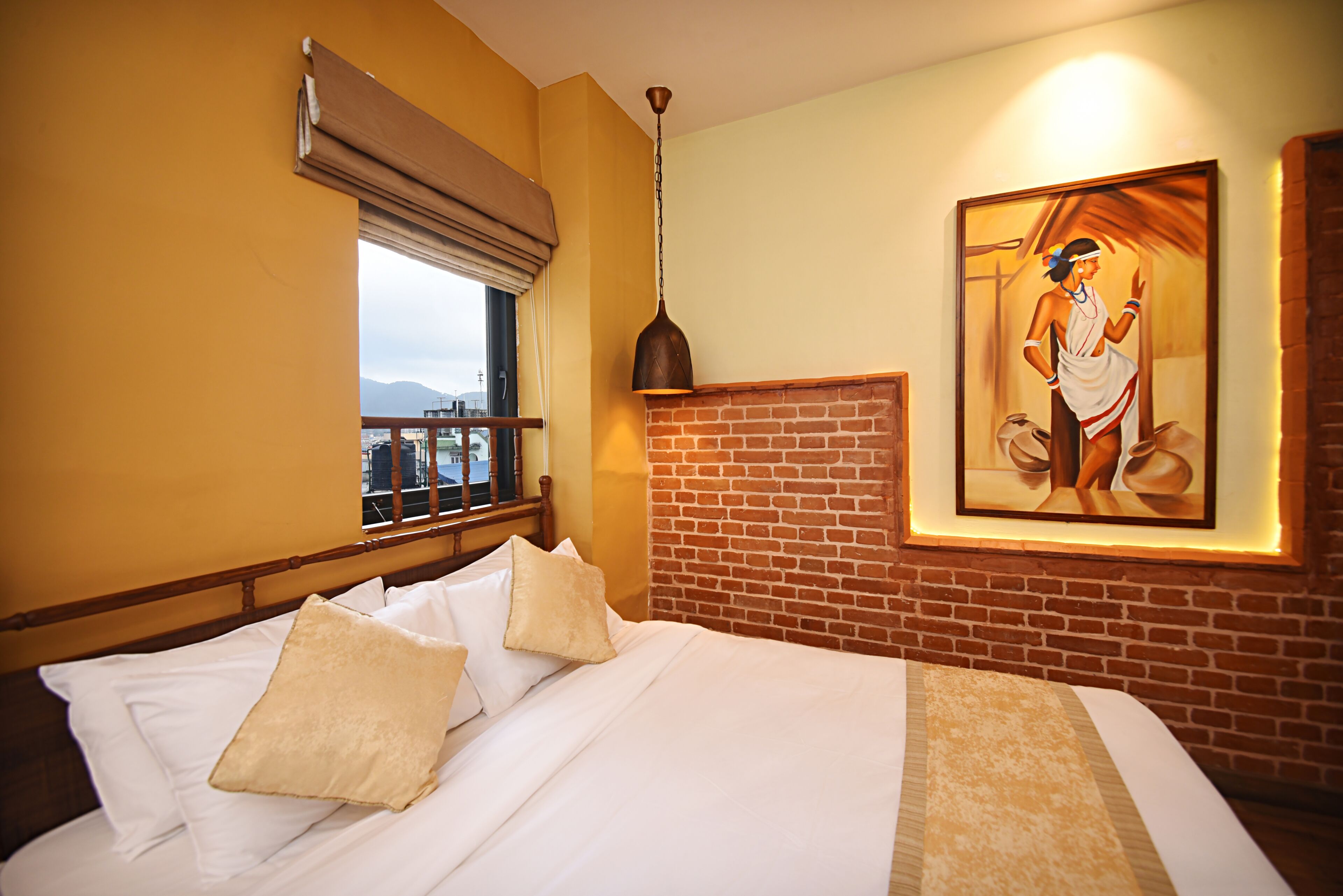 Ein Hotelzimmer mit Bett, Fenster mit Blick, einer Ziegelwand und einem Gemälde.