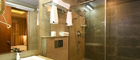 A modern bathroom with a glass shower enclosure, a white sink, and a toilet.
