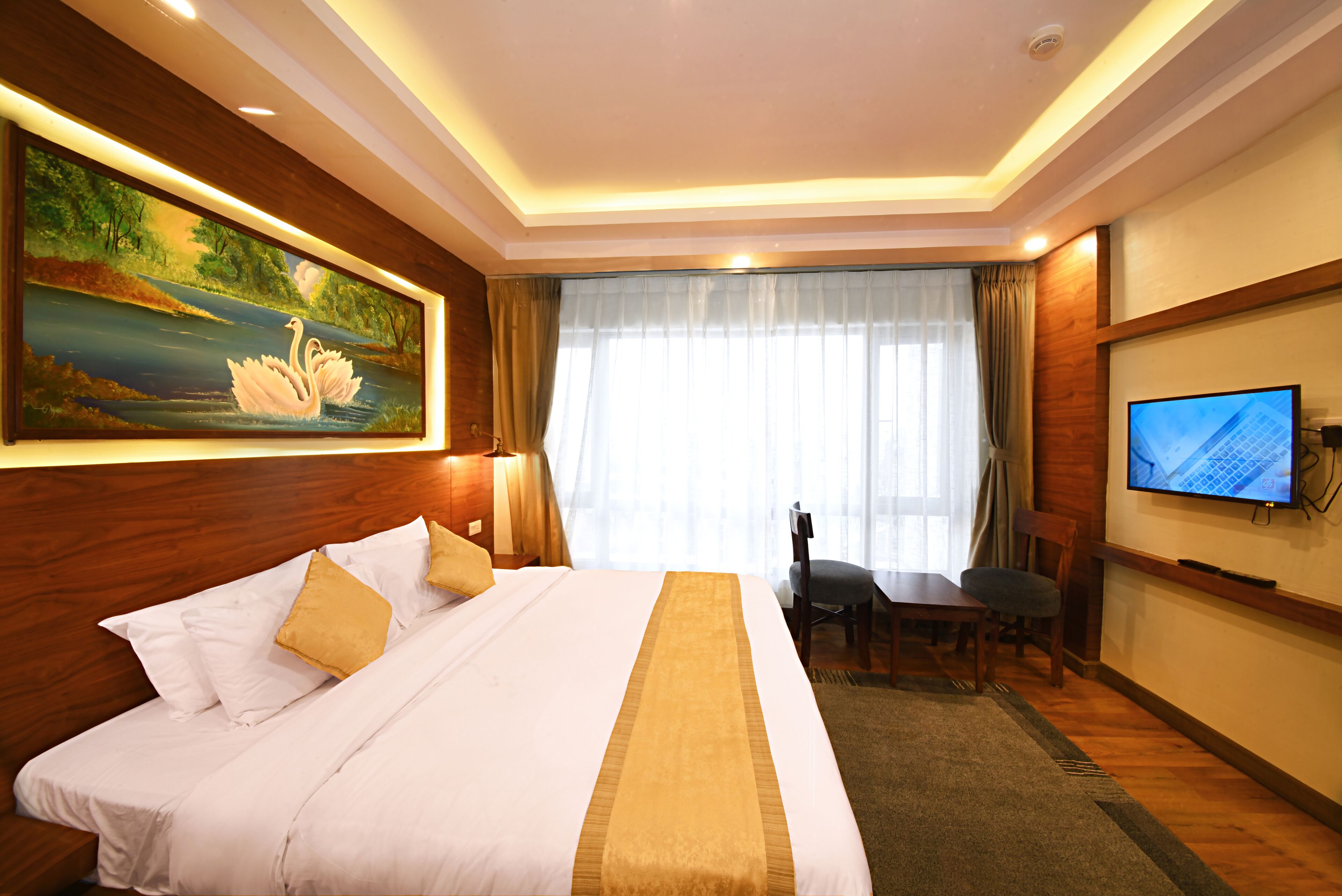 A hotel room with a large bed, a desk, and a television.