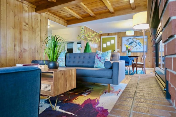 A cozy living room with a blue sofa, wooden coffee table, and a colorful rug.