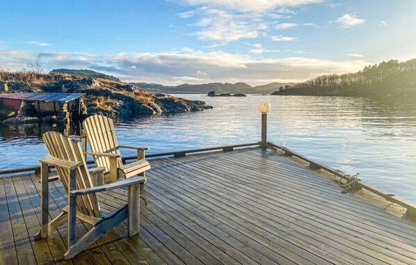 Relax on the deck overlooking the serene lake with a picturesque view of the surrounding hills.