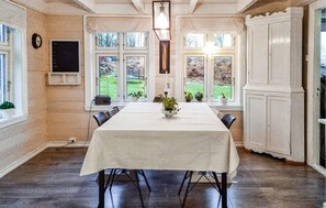 Enjoy meals in this elegant dining room with a long table for four, a high ceiling, and a beautiful garden view.