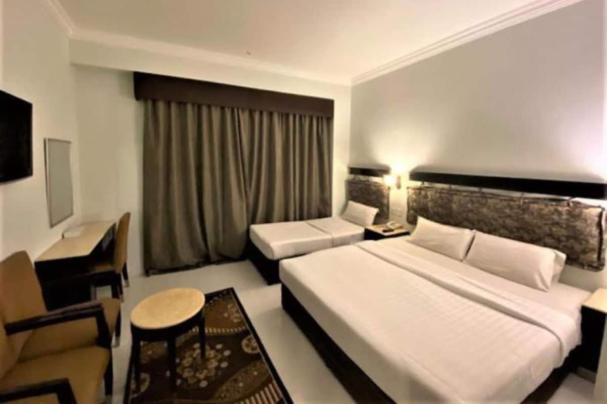 A hotel room with a large bed, two bedside tables, a desk, a chair, and a TV.