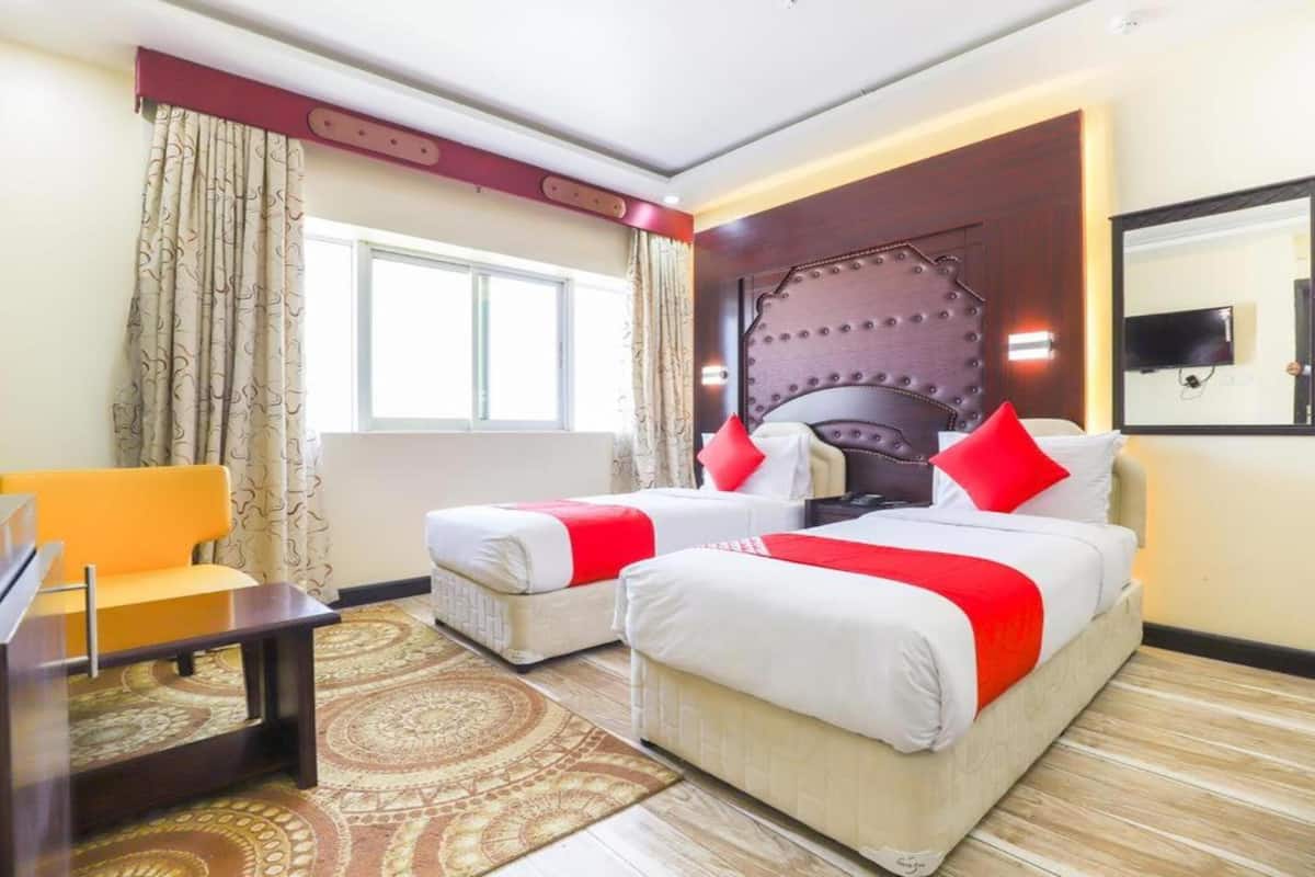 A hotel room with two beds, a desk, and a chair.