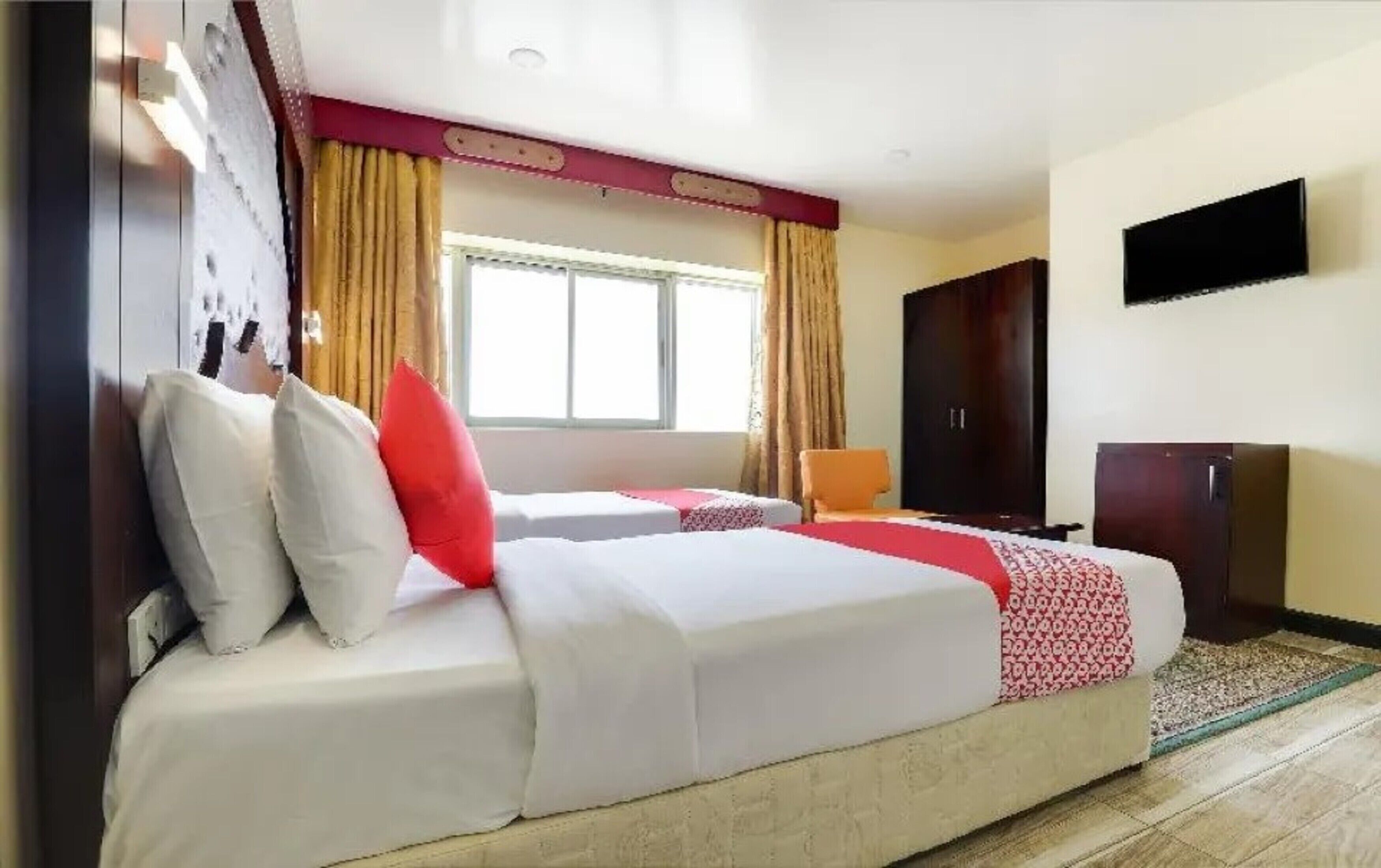 Una habitación de hotel con cama, una silla, armario y televisión en la pared.