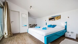 A modern bedroom with a bed, a nightstand, a window with curtains, and a painting on the wall.