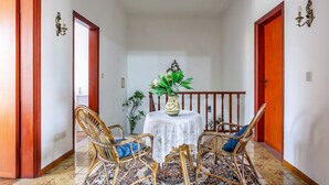 A hallway with a round table, wicker chairs, a patterned rug, and a potted plant.