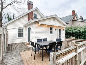Een huis met een terras, een eettafel met stoelen en lichtjes.