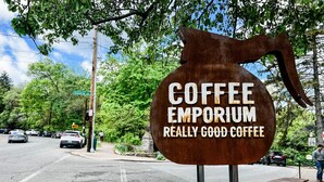 Une enseigne pour Coffee Emporium, avec l’inscription « EXCELLENT CAFÉ » sur une structure métallique marron.