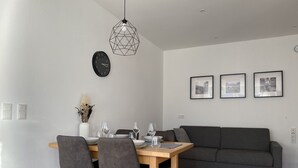 Ett modernt matområde med ett träbord, grå stolar och en grå soffa.