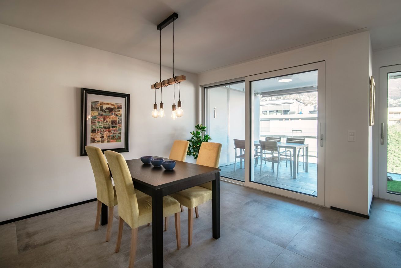 Een eethoek met een donker houten tafel, gele stoelen en een hangende lamp.