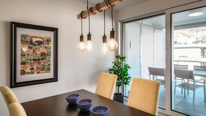 A dining area with a wooden table, three chairs, and a framed poster on the wall.