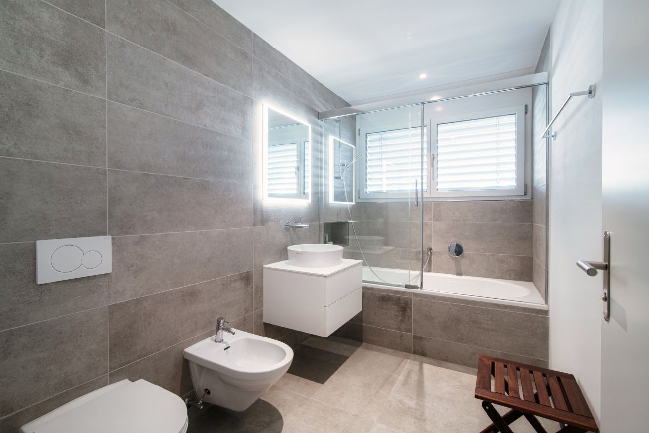 A modern bathroom with a bidet, sink, and bathtub.