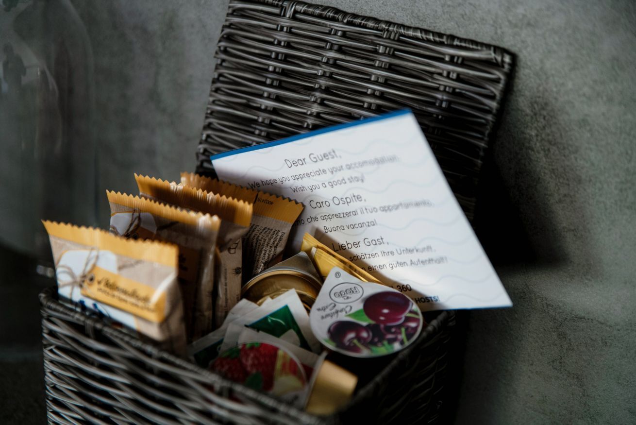 Un panier en osier rempli de divers produits alimentaires et une note adressée à un invité.