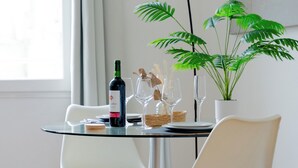 Una mesa de comedor con dos sillas blancas, una botella de vino y una planta en maceta.