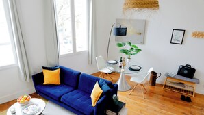 Una sala de estar moderna con un sofá azul, una mesa de comedor de vidrio y una mesa de centro.