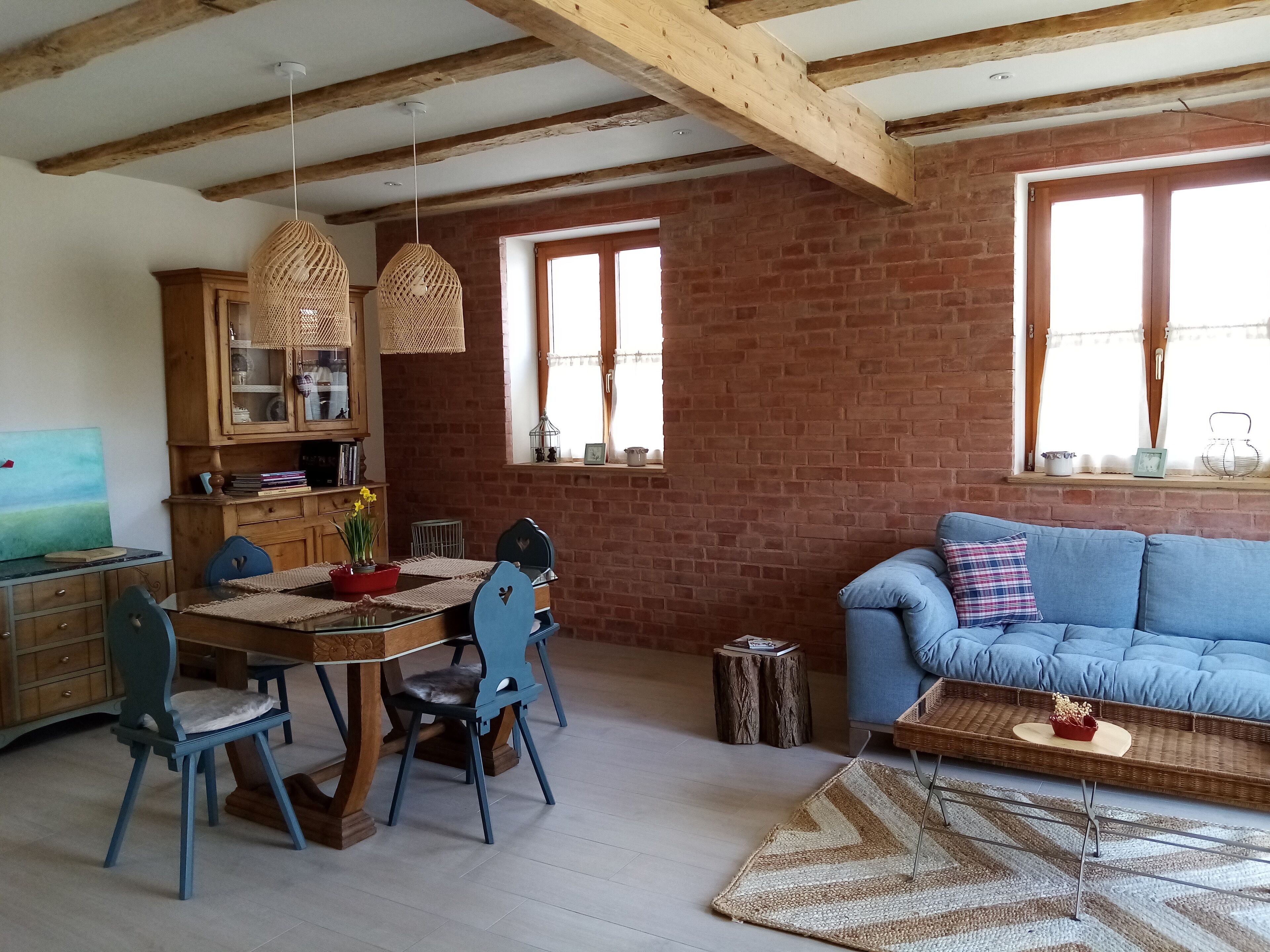 Een gezellige woonruimte met een eethoek, een blauwe bank en een houten eettafel met stoelen.