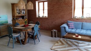 Ein gemütlicher Wohnbereich mit Essplatz, einem blauen Sofa und einem Holzesstisch mit Stühlen.