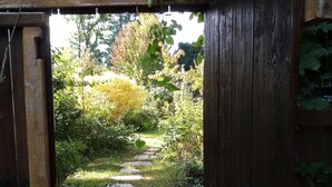 Ein hölzernes Tor führt zu einem gepflasterten Weg, der von Grün umgeben ist.