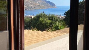 Blick von einem Balkon auf einen klaren, blauen Himmel, einen Berg in der Ferne und ein Gewässer.