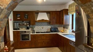 Eine Küche mit einem Steingewölbe, Holzschränken, einem Edelstahlkühlschrank und einem gefliesten Boden.