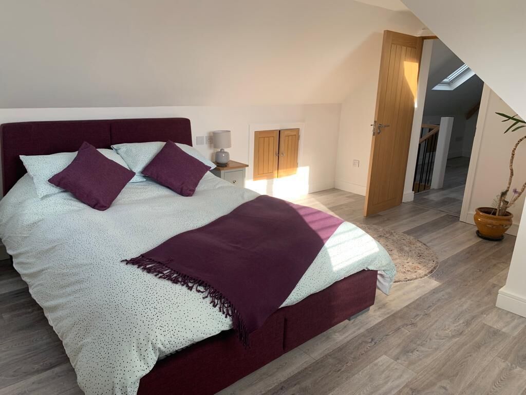 Une chambre à coucher avec un grand lit, une table de chevet, une armoire en bois et une plante en pot.
