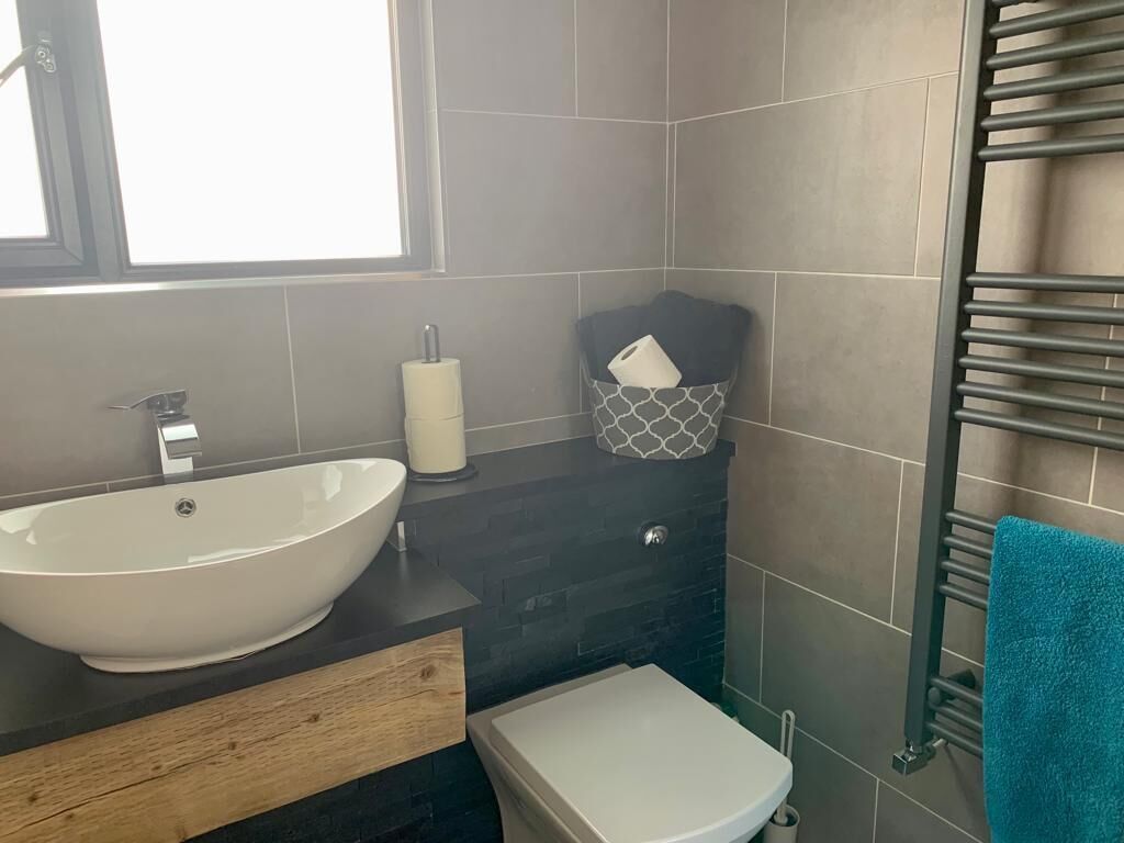 Et badeværelse med en stor hvid vask, et toilet og en håndklædeholder.