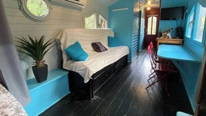 A compact cabin-style room with a bed, a small table, a chair, and a potted plant. - Roulotte with air conditioning and private pool in Tourtour (Tourtour)
