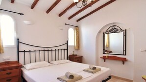 A bedroom with a bed, wooden nightstands, a mirror, and a window. - Ina's vacation home (Teulada)