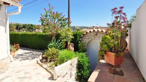 A narrow courtyard with a stone archway, potted plants, and a tiled pathway. - Ina's vacation home (Teulada)
