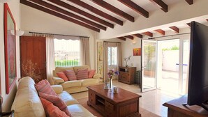 A living room with a sofa, coffee table, and a television. There is a door leading to an outdoor area. - Ina's vacation home (Teulada)