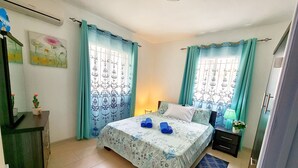 A bedroom with a bed, a nightstand, a lamp, and a window with curtains. - Your little paradise at the end of the world - 100m from the beach (Flic en Flac)