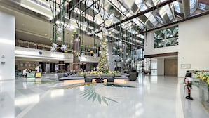 A spacious lobby with a large Christmas tree, seating areas, and a high ceiling with skylights. - WelHome - Deluxe Apartment With Panoramic Sea Views (Dubai)