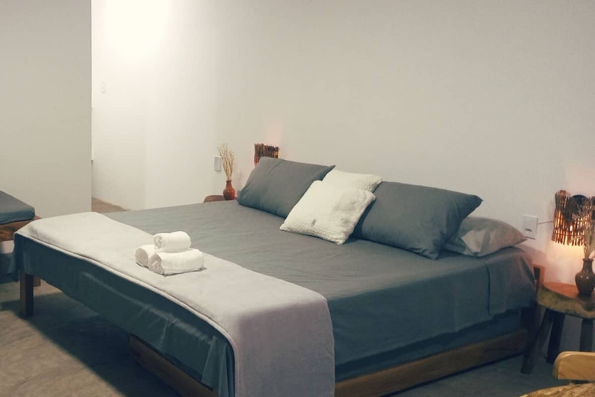 Ein Schlafzimmer mit einem Einzelbett, einem kleineren Bett und einem Nachttisch mit Lampe.